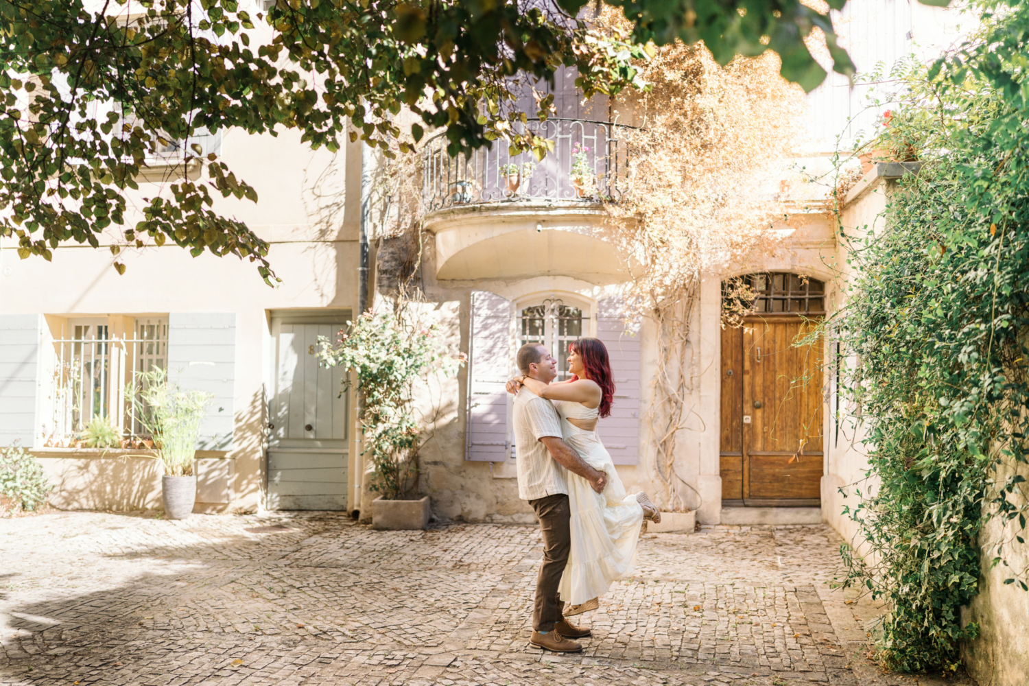 man lifts woman in cute courtyard in arles france