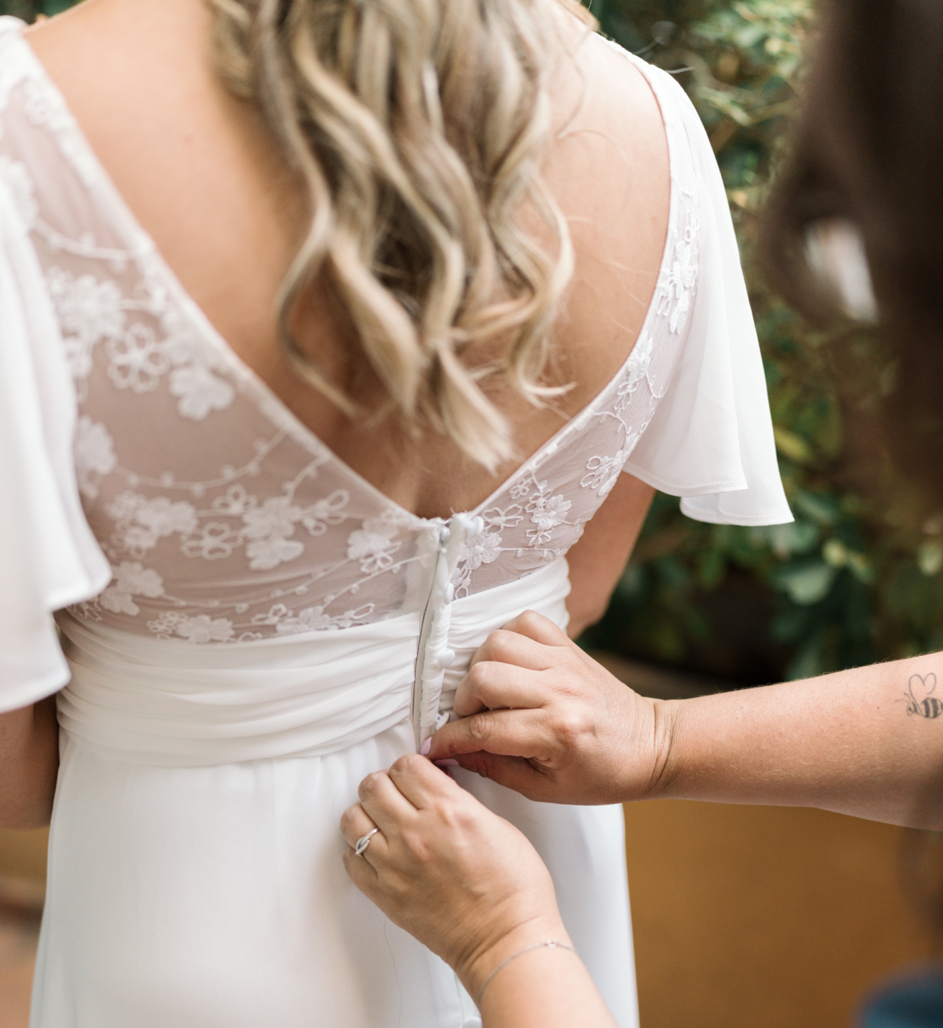 mother helps bride with wedding gown