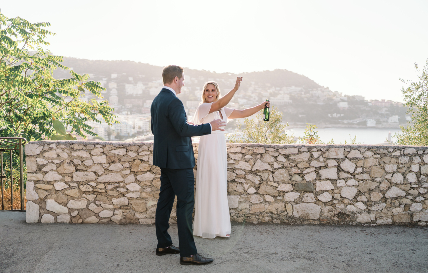 bride pops the cork on champagne on her wedding day in nice france
