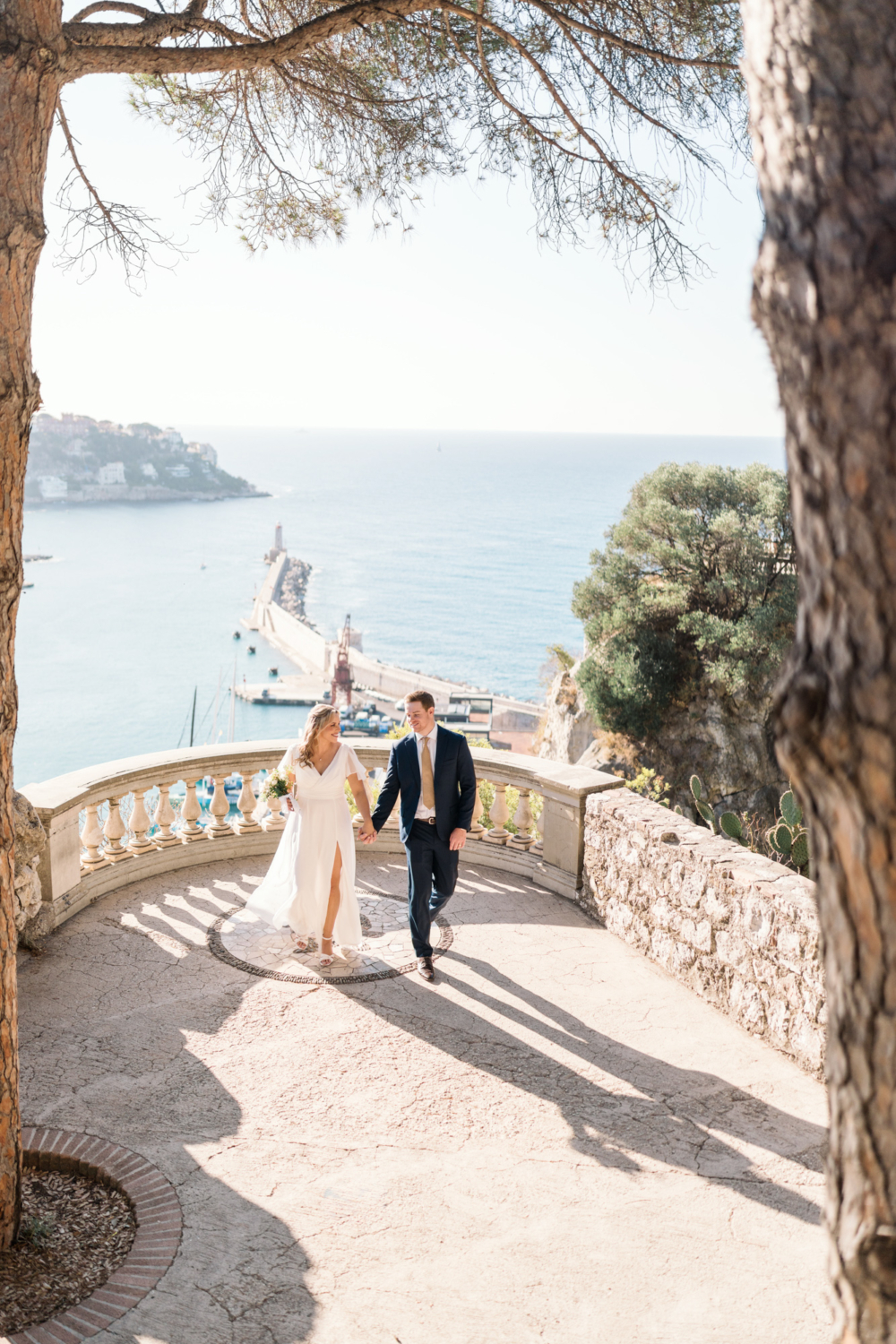 bride and groom walk with view of lighthouse in nice france