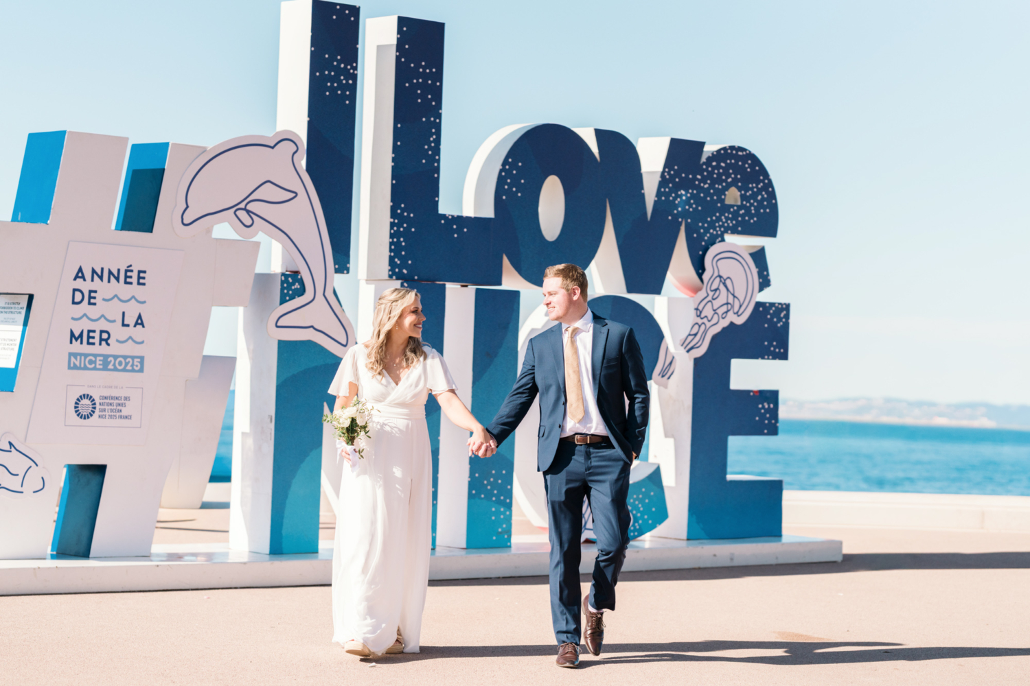 bride and groom walk in front of i love nice sign in nice france