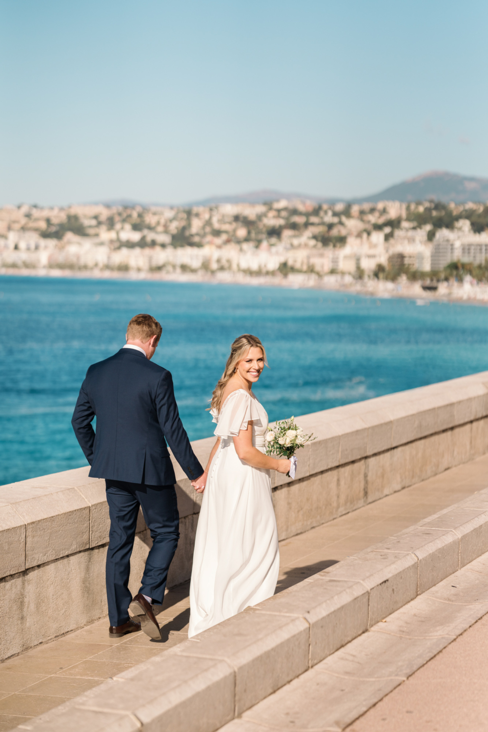 bride looks radiant as she walks along the sea in nice france