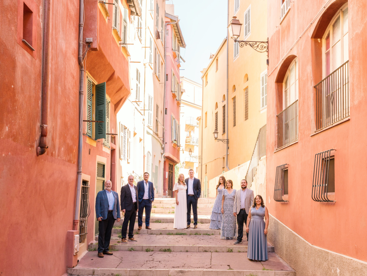 bride and groom walk surrounded by their family in old town nice france