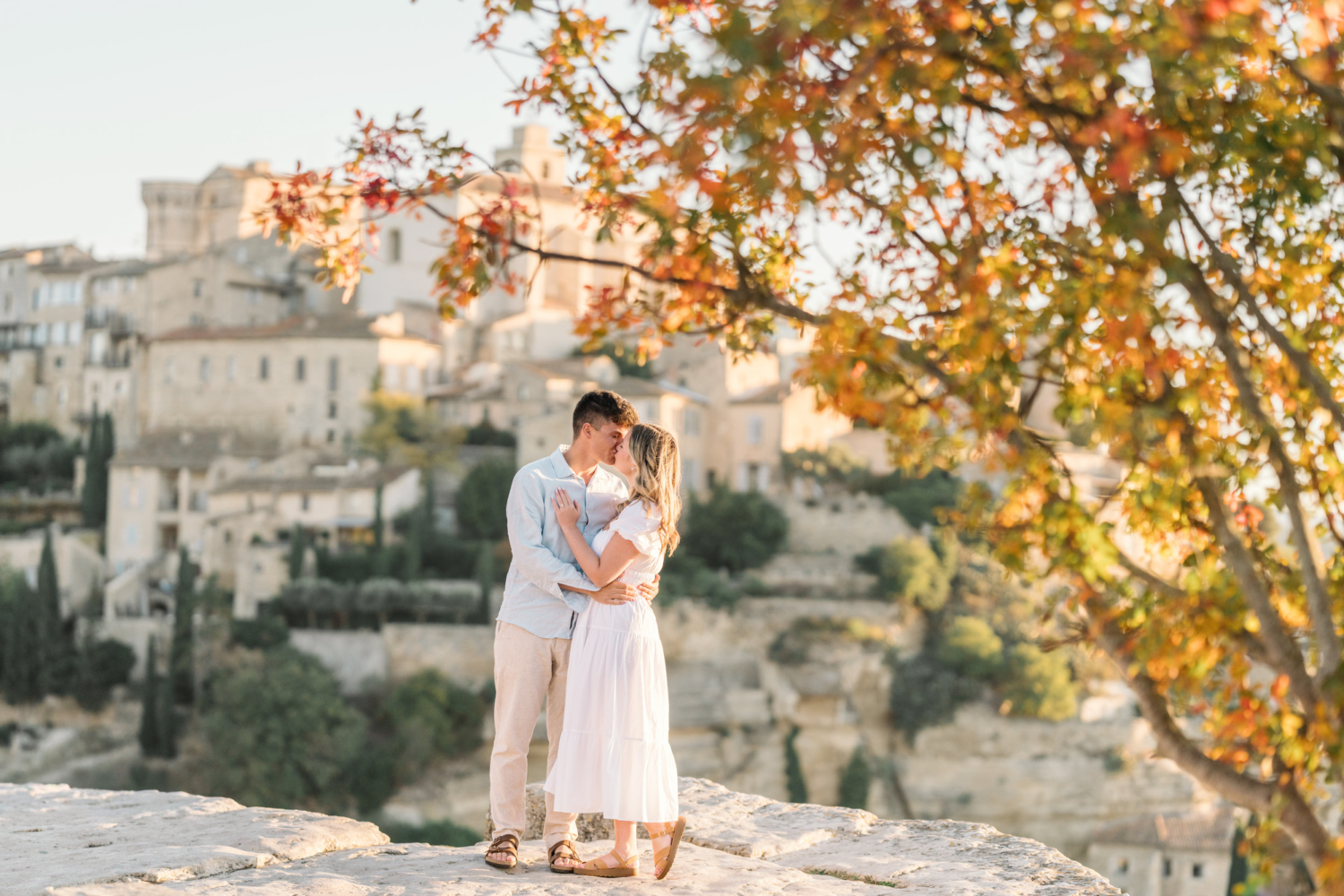 engaged couple kiss surrounded by autumn leaves in gordes, provence france