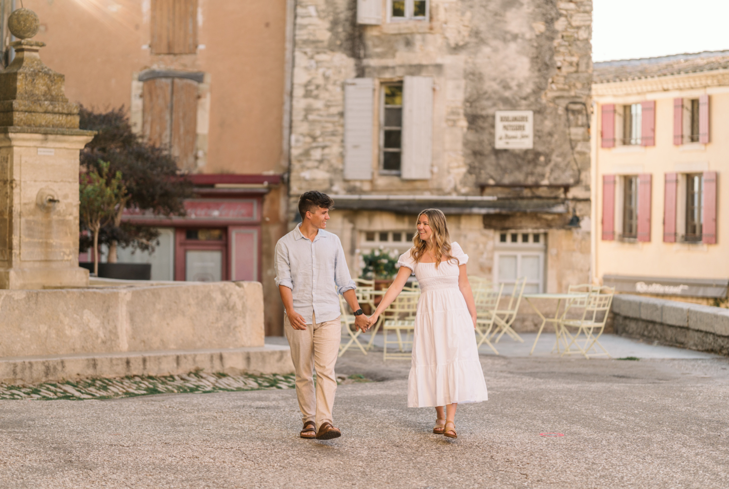 engaged couple walk hand in hand in gordes, provence france