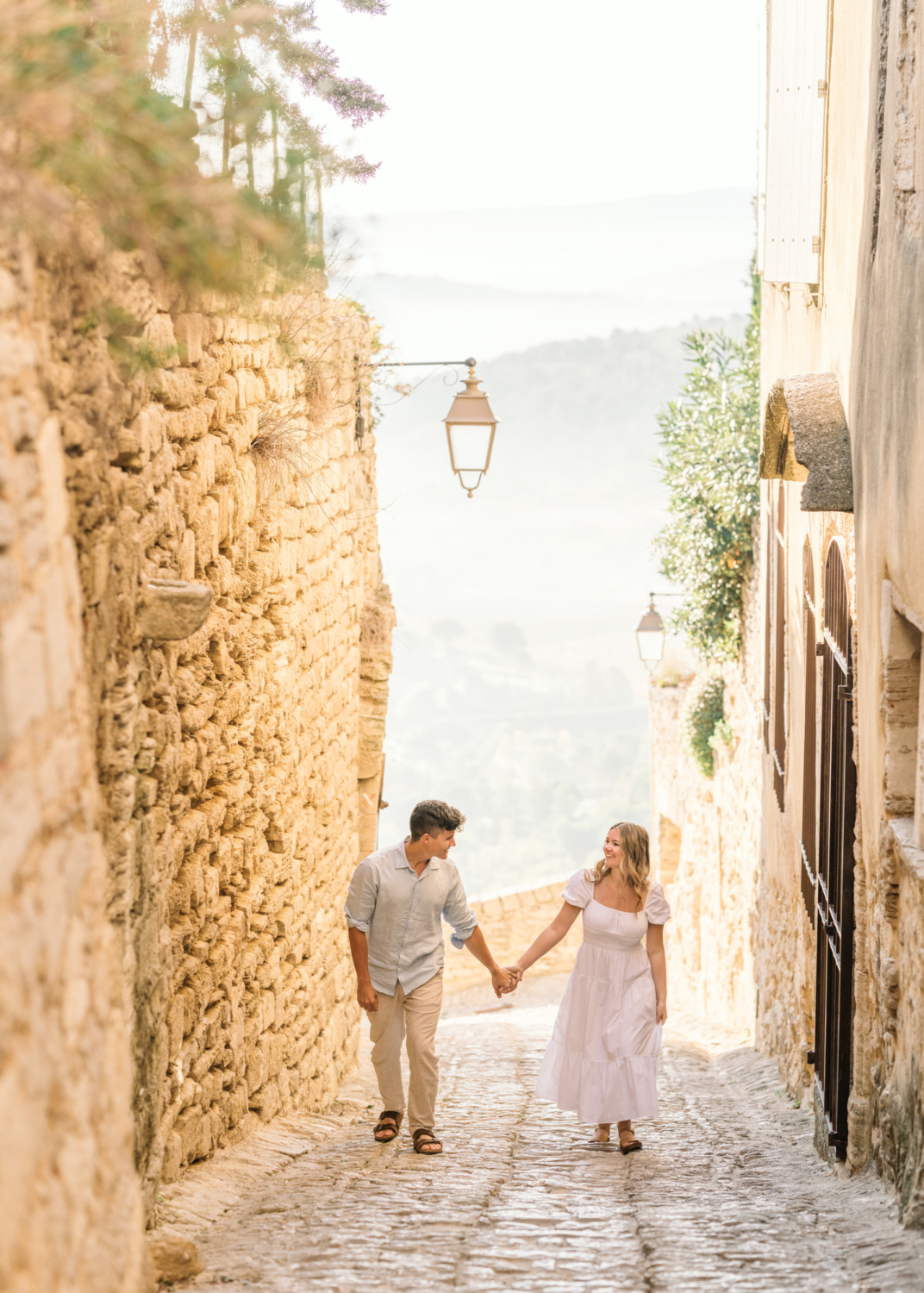 engaged couple walk at sunrise in gordes, provence france