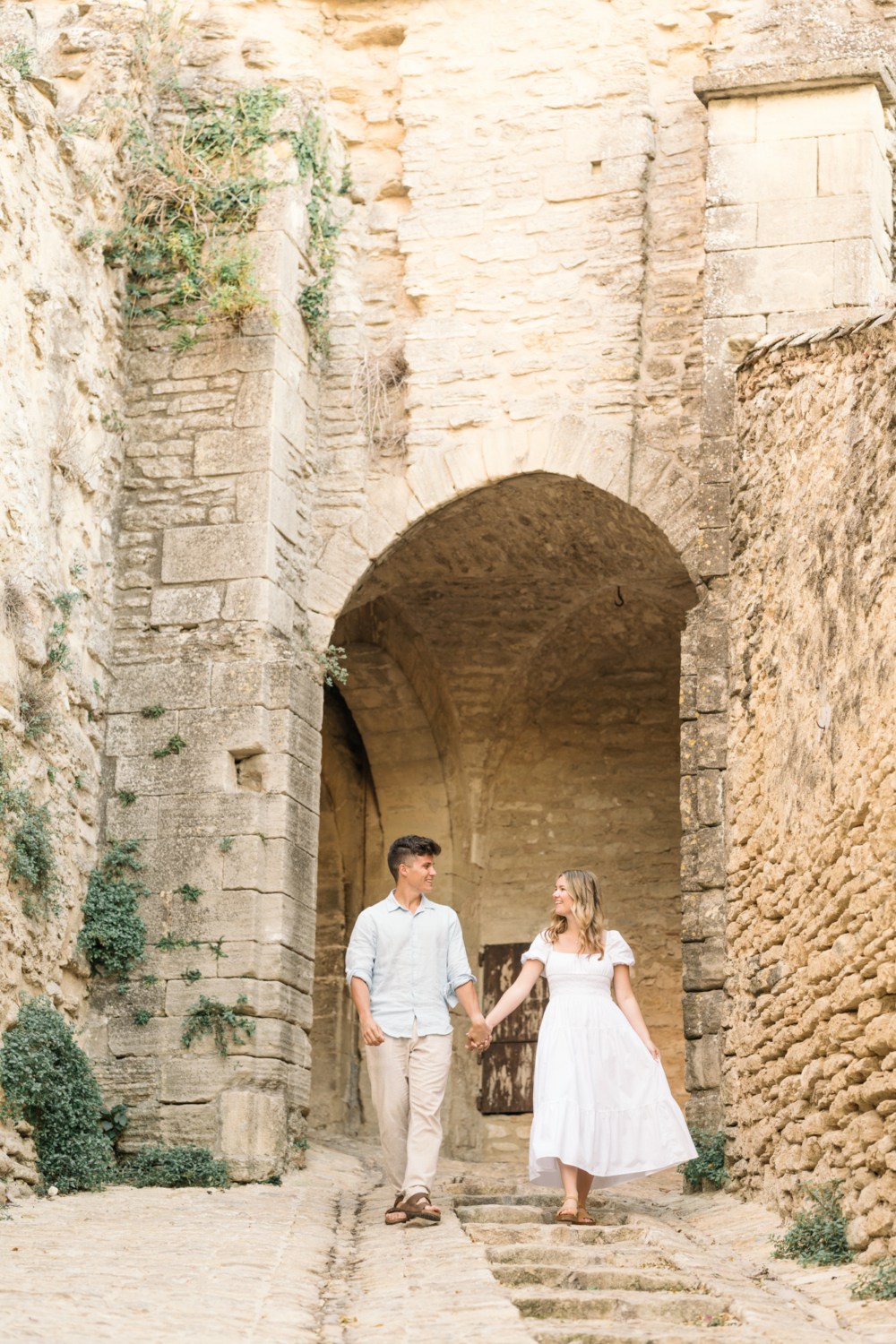 engaged couple walk down cobblestones in gordes, provence france