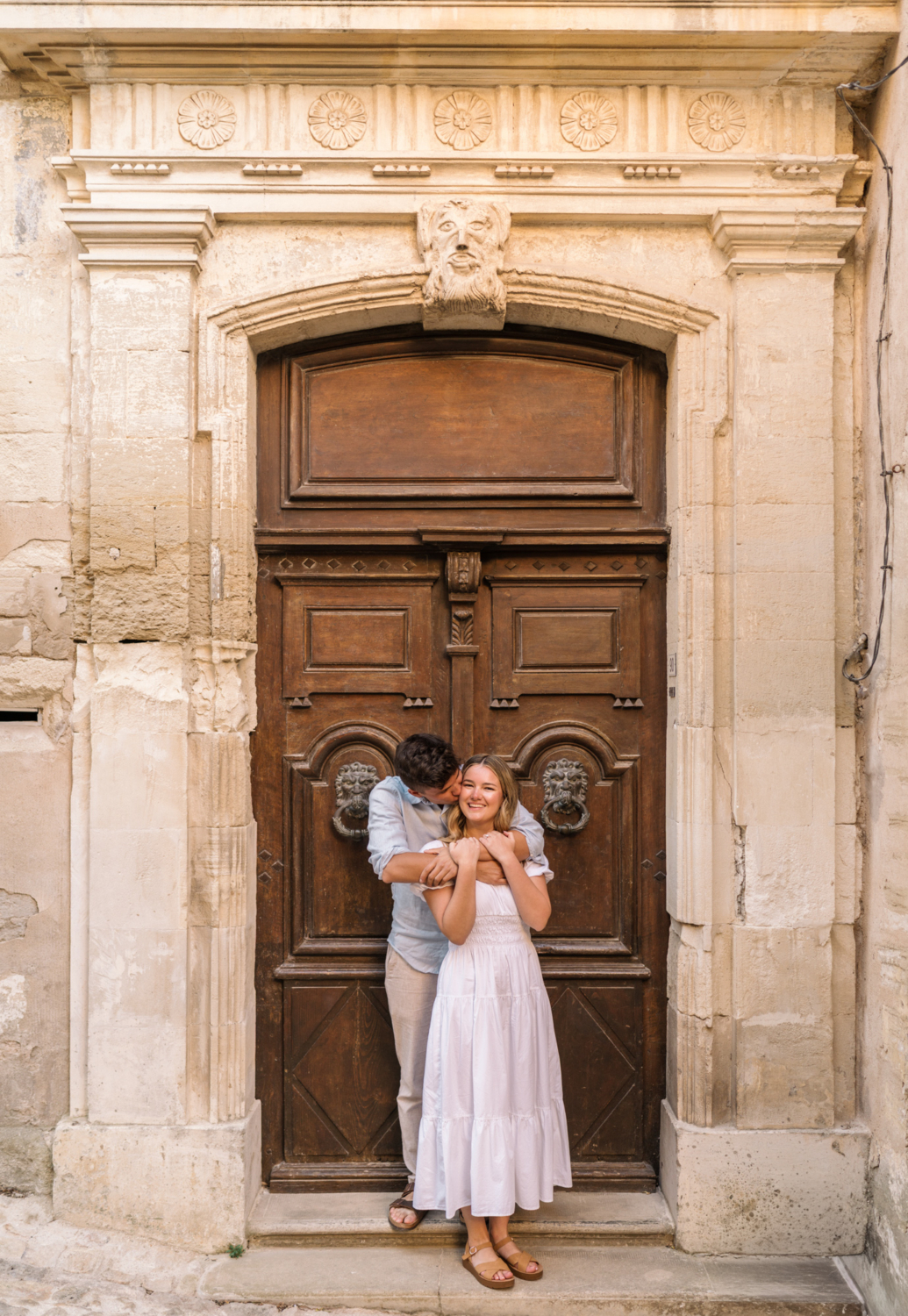 engaged couple pose in front of ornate door in gordes, provence france