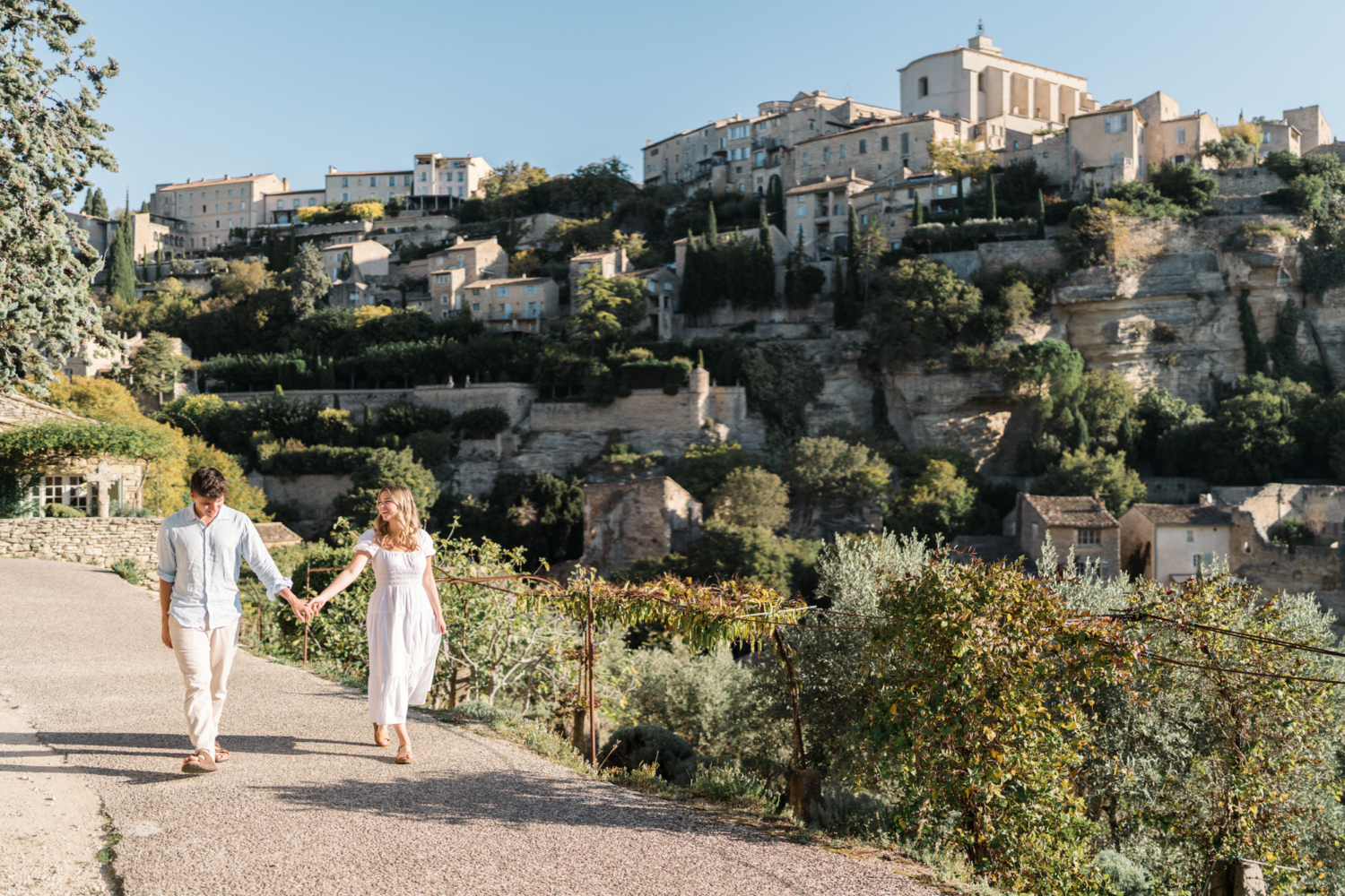 engaged couple walk through the village of gordes, provence france