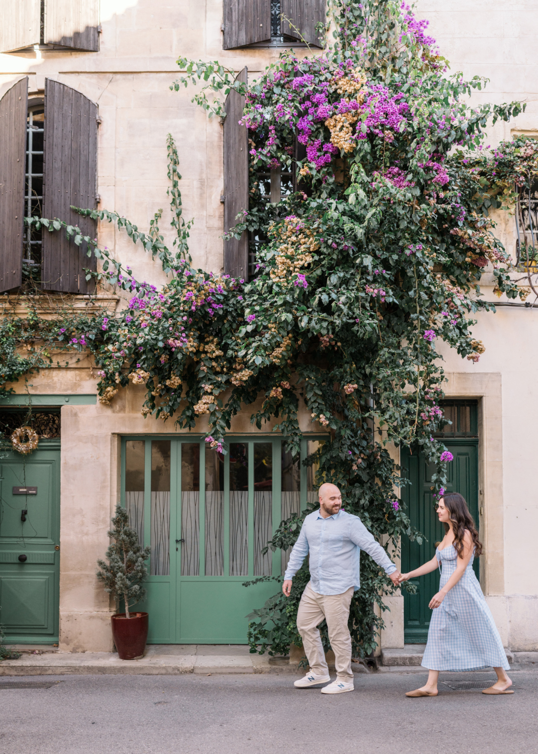 engaged couple walk in front of green door in arles france
