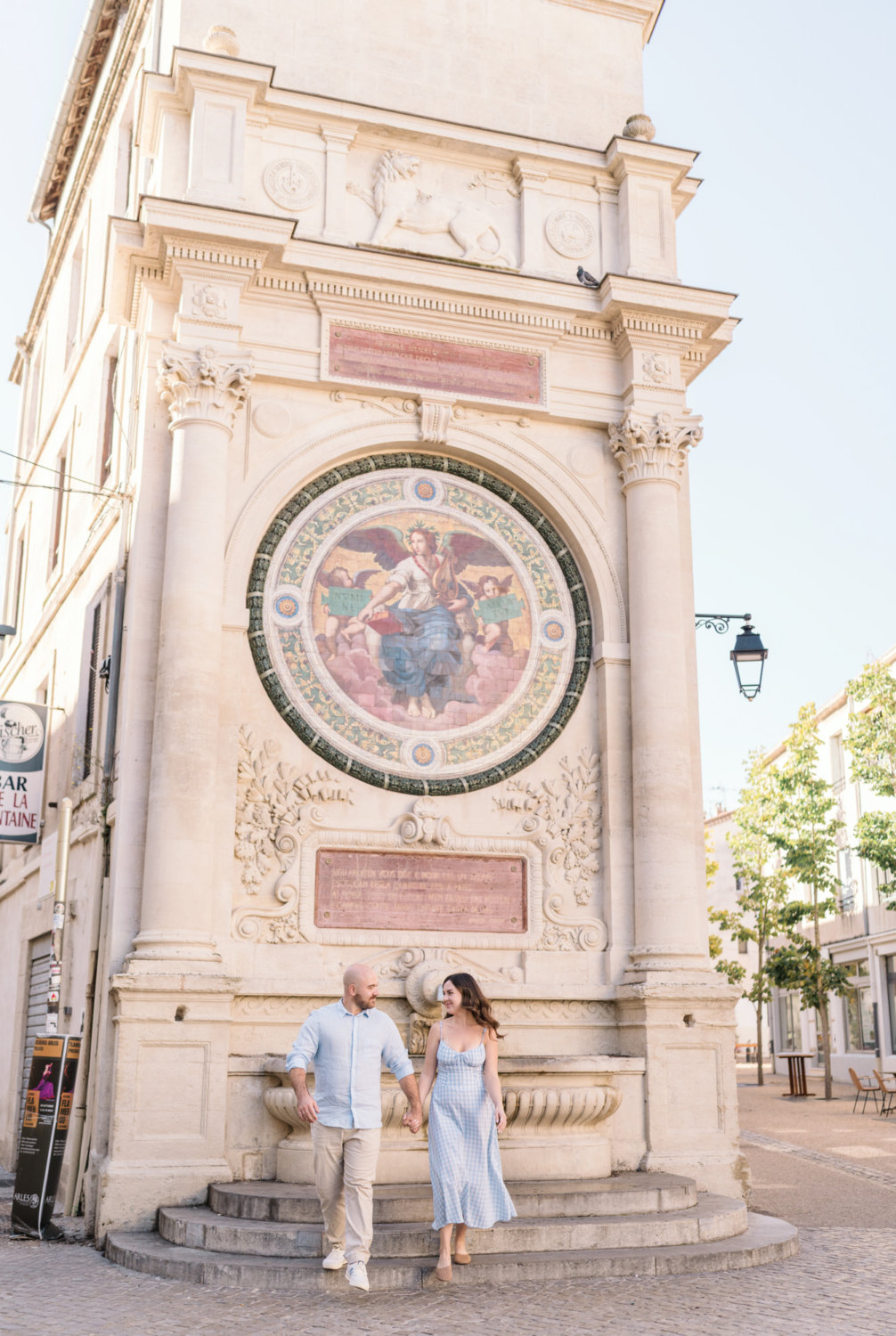 engaged couple walk in front of fountain in arles france