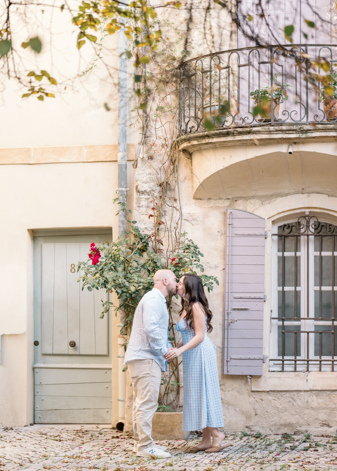 engaged couple kiss in front of rose bush in arles france