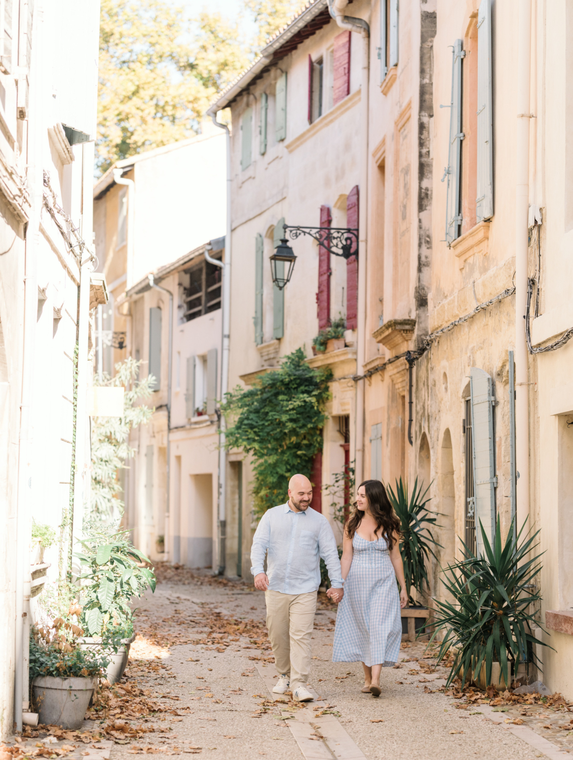 happy engaged couple walk hand in hand in la roquette neighborhood in arles france