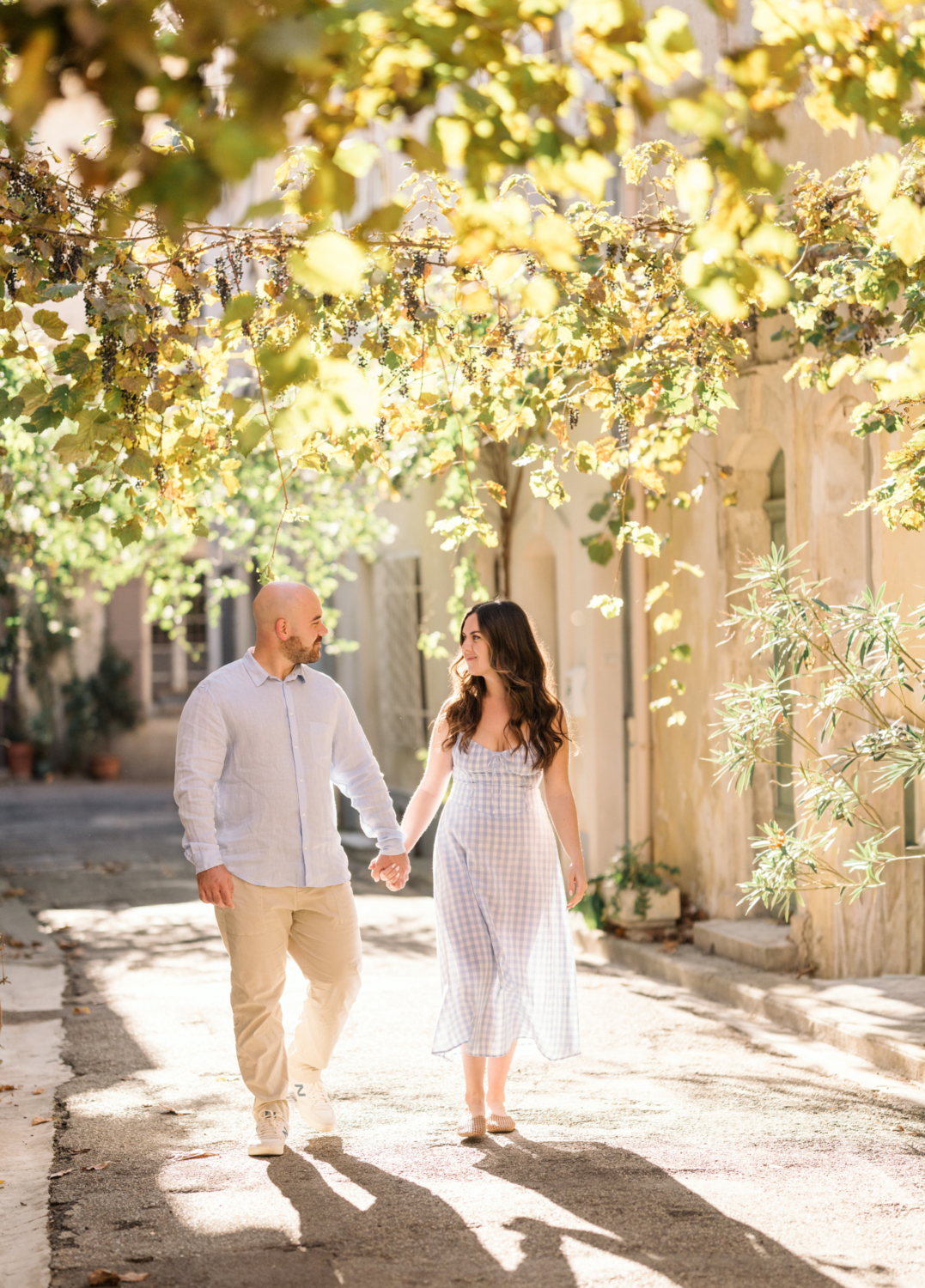 engaged couple walk on sunlit street in arles france