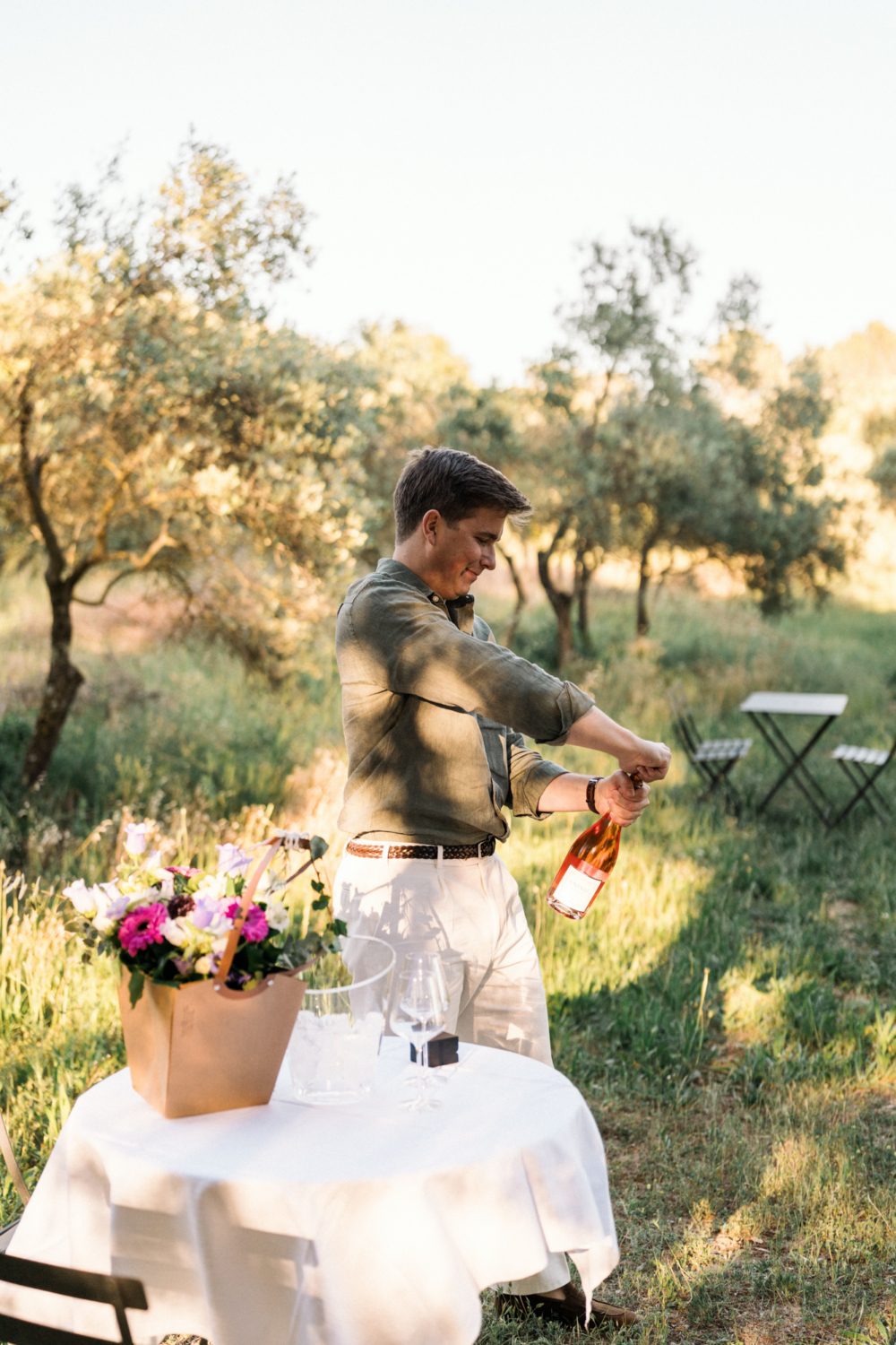 man pops cork on wine bottle in provence france