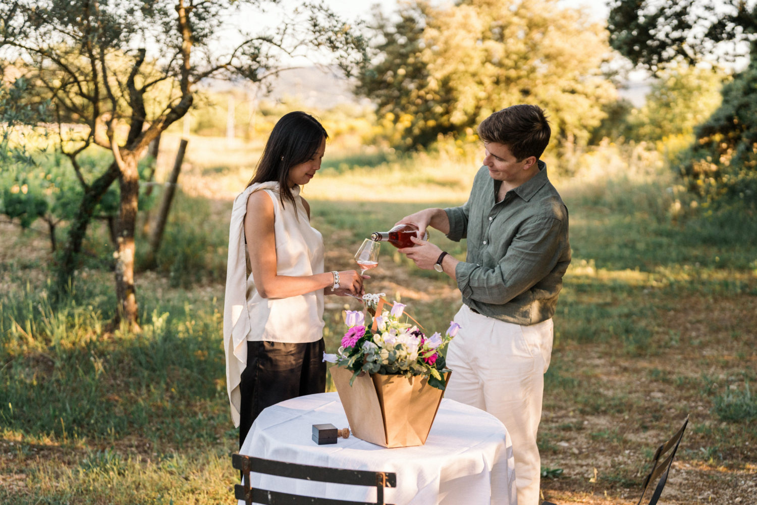 man pours wine in glass for his fiancee in provence