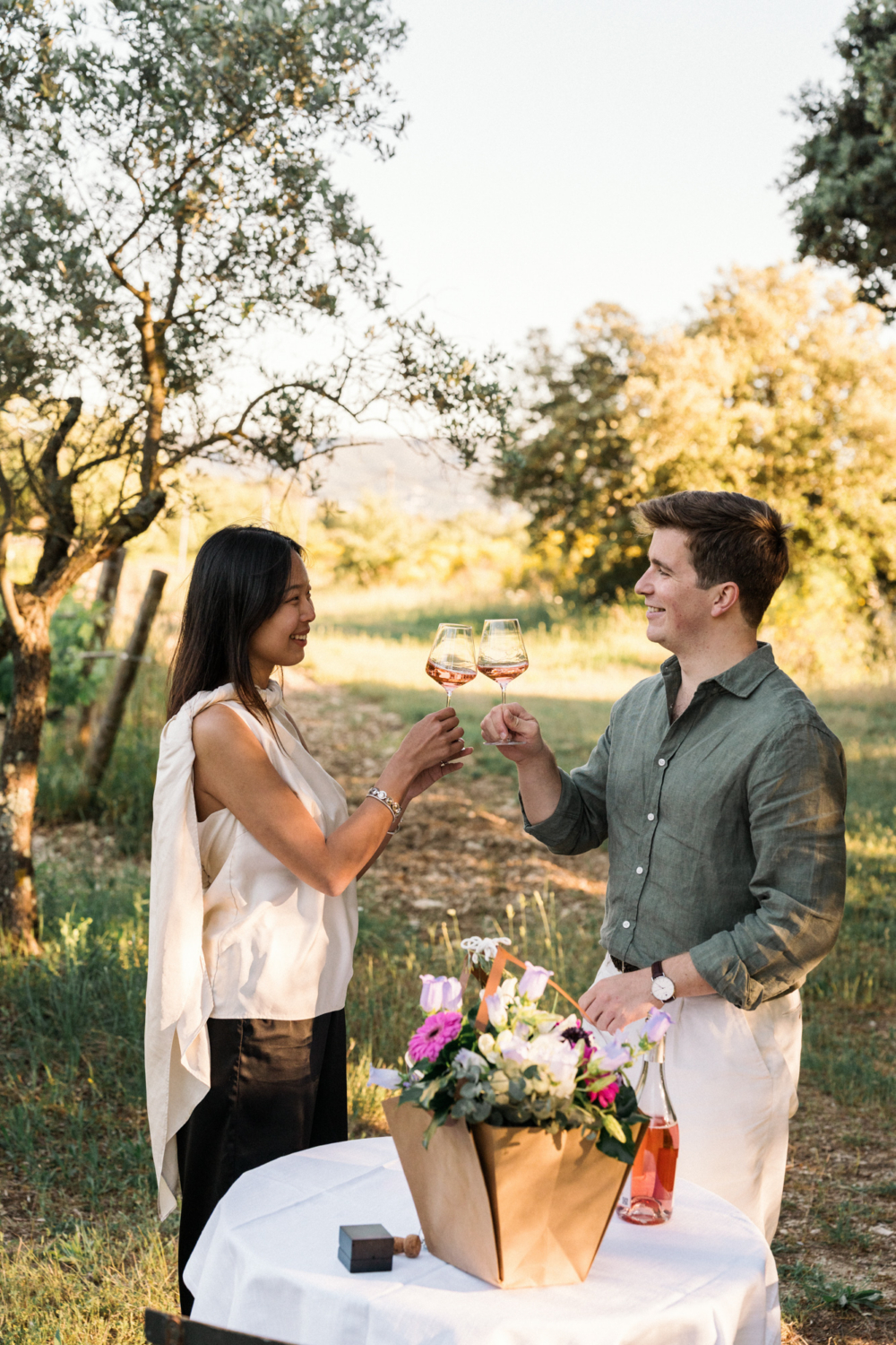 newly engaged couple toast each other in vineyard
