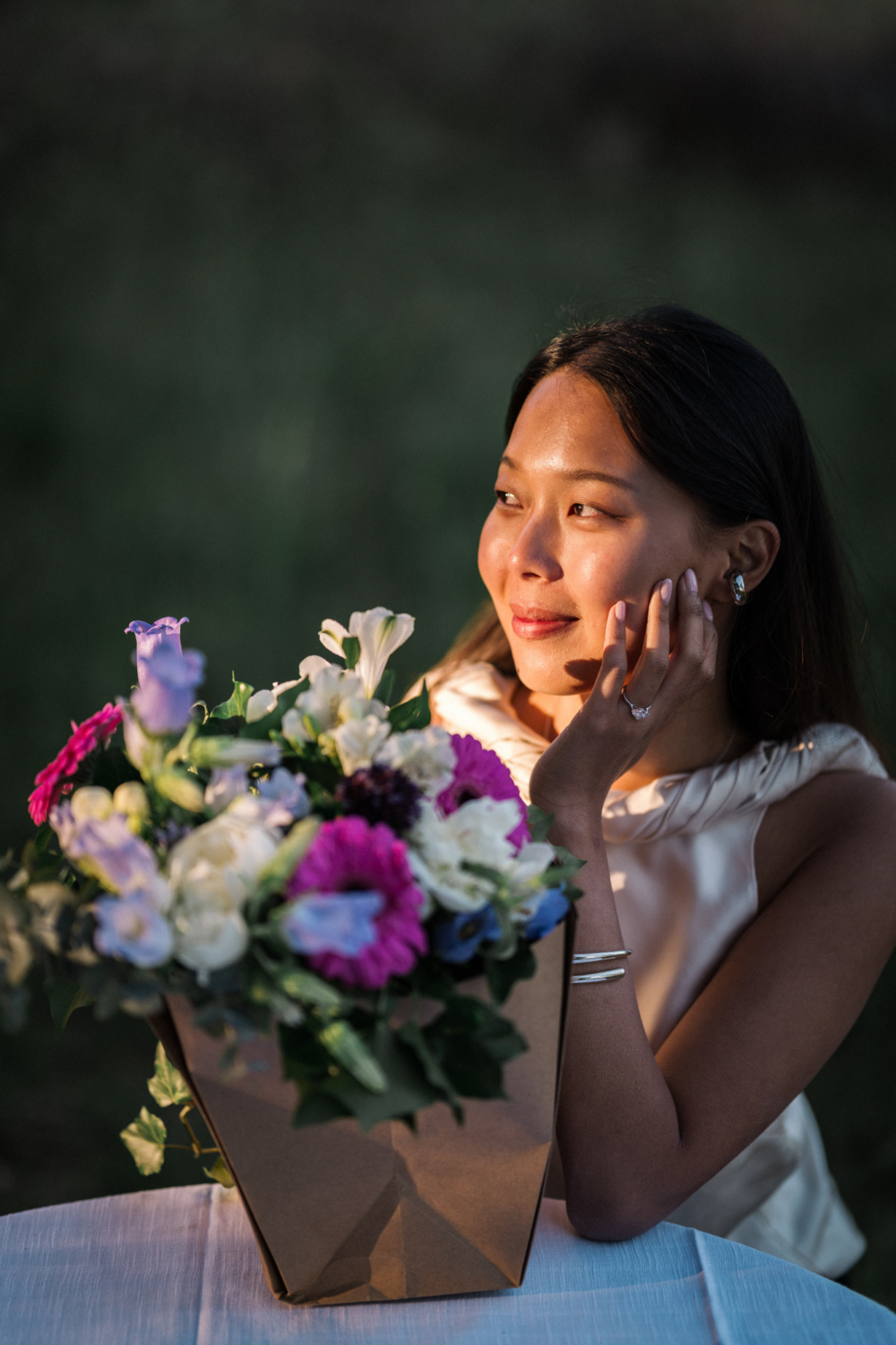 woman sits in the sun with flowers after her engagement in provence