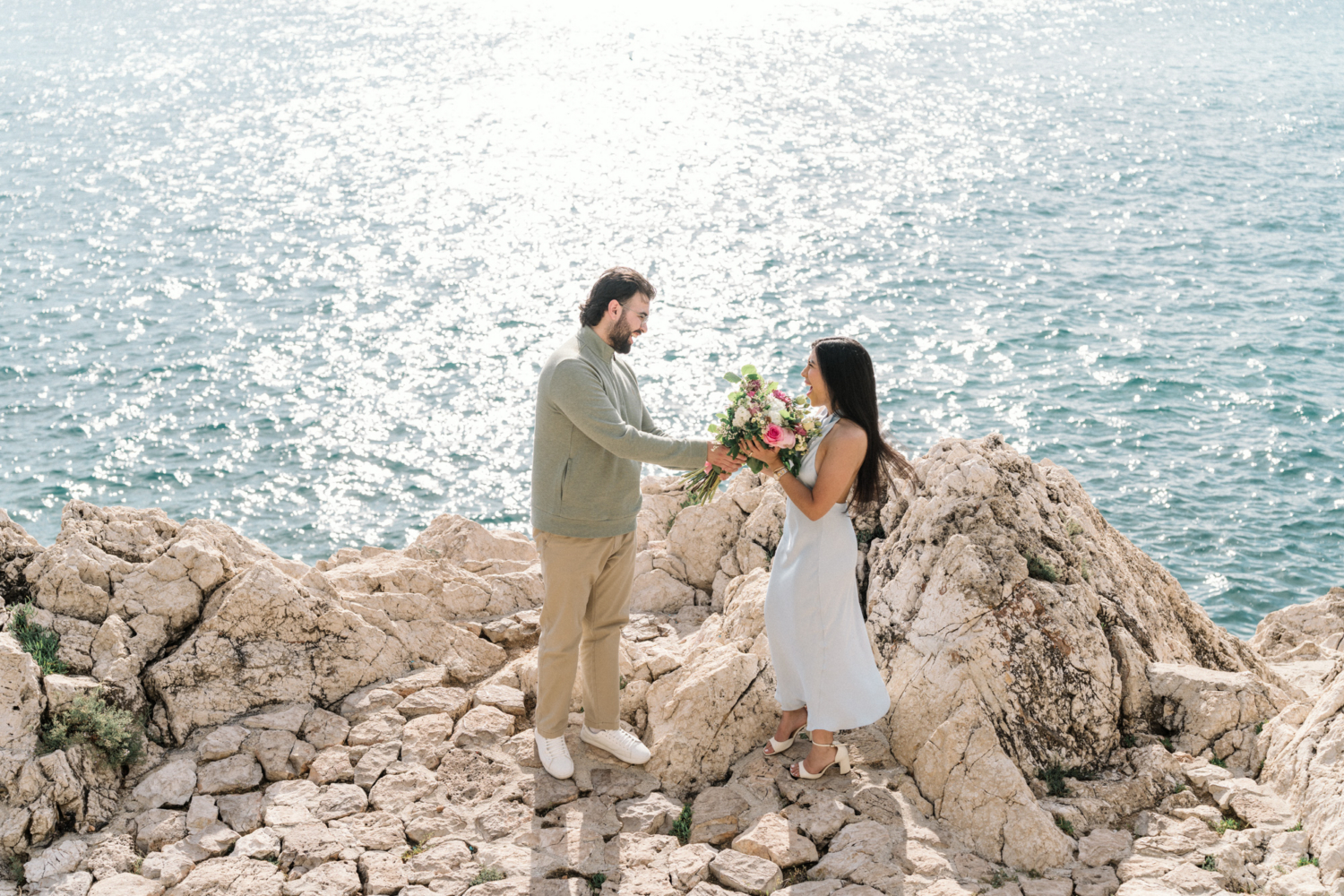 man presents bouquet to woman at their engagement in nice, framce