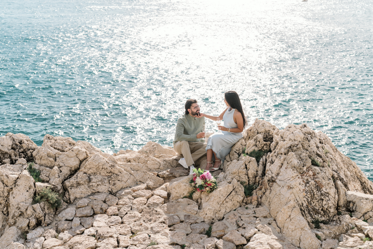 woman touches man's chin with view of the sea