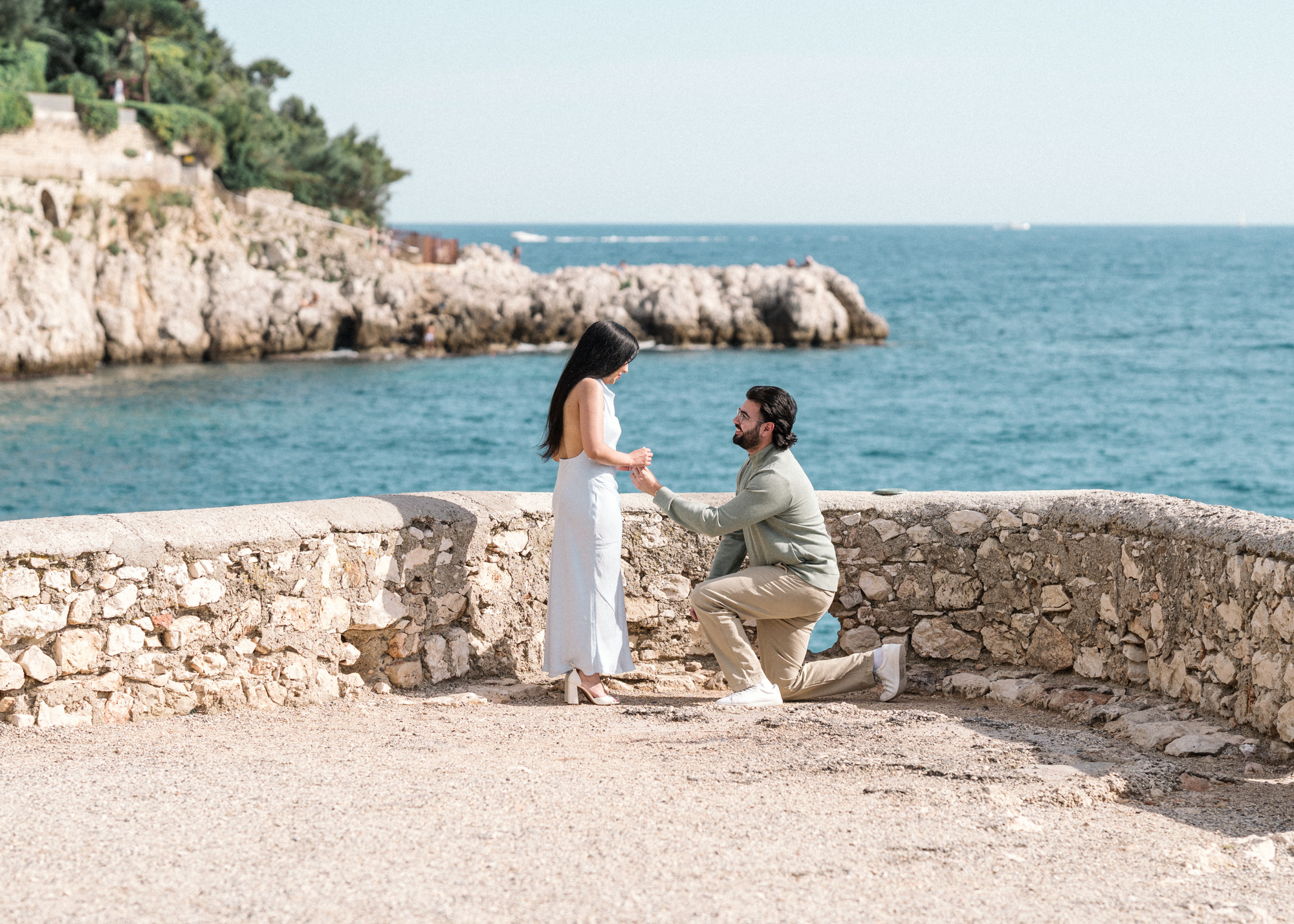 man proposes to woman with view of mediterranean sea in background