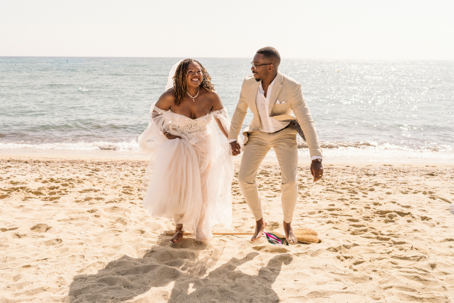 bride and groom jump the broom on the beach in saint tropez