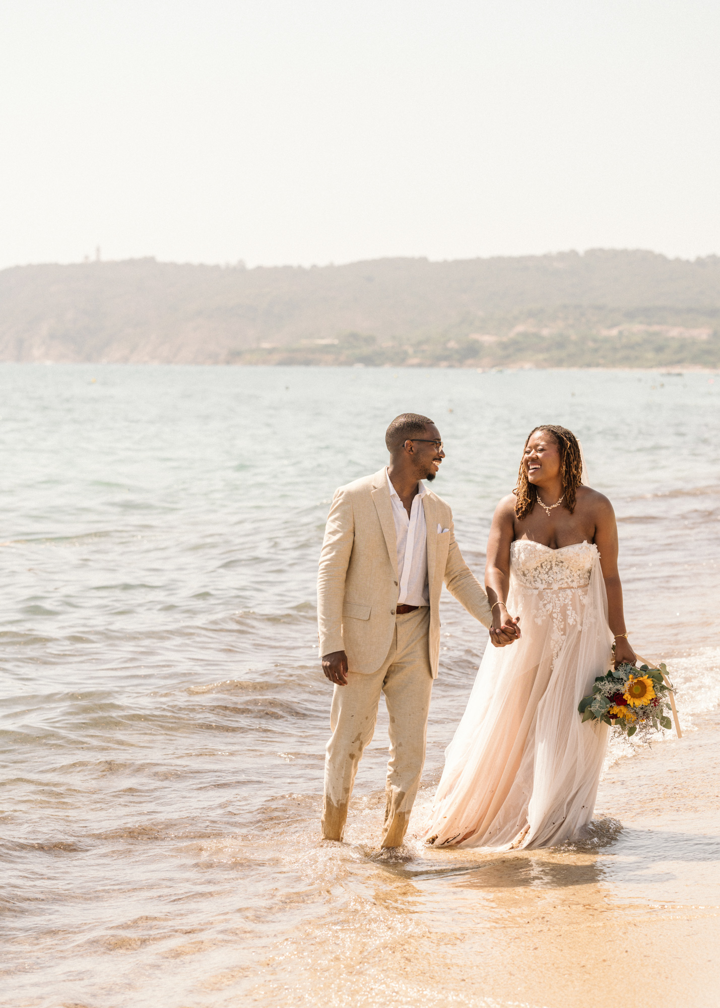bride and groom laugh and walk on the beach in saint tropez