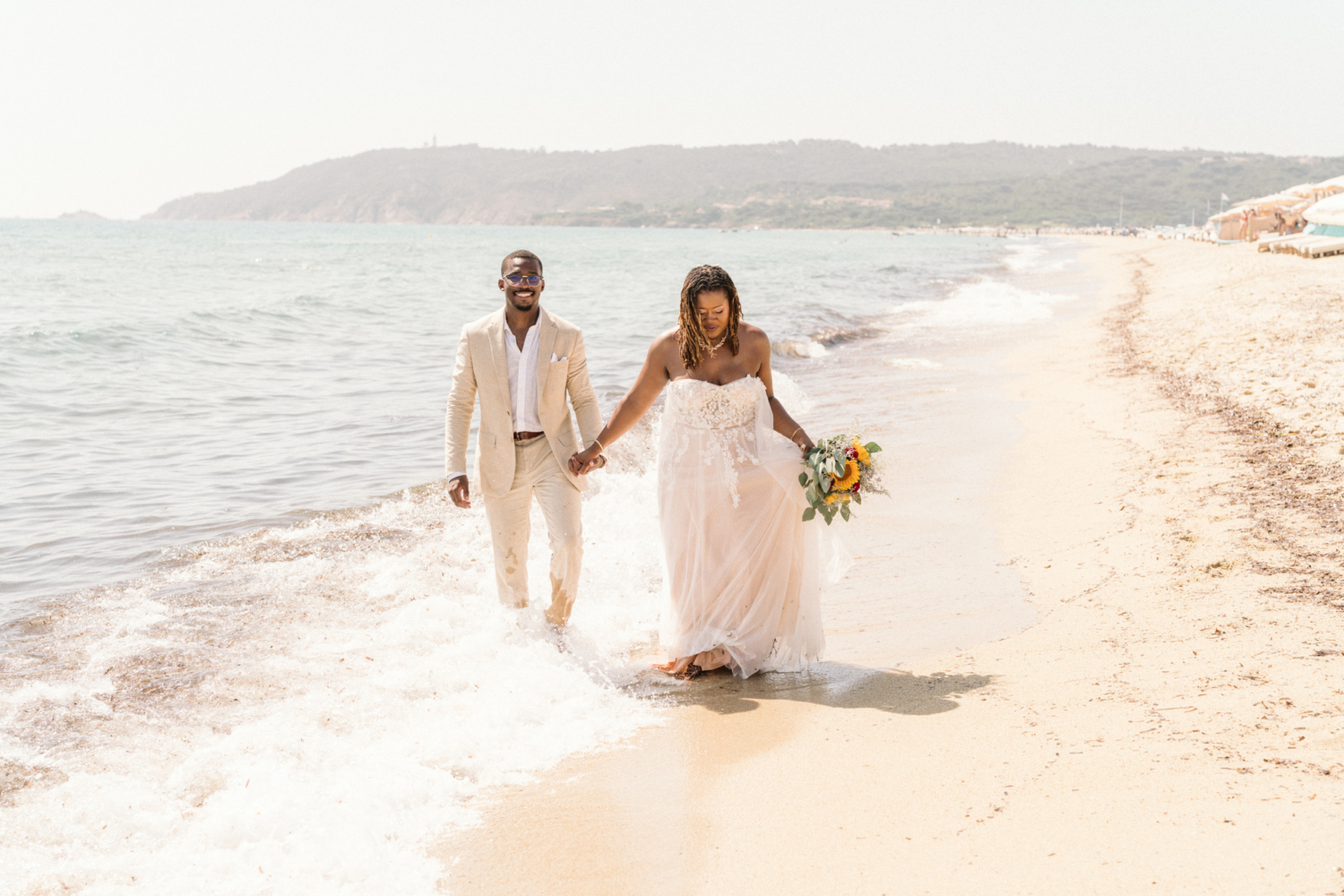 bride and groom walk on the beach in saint tropez after their wedding